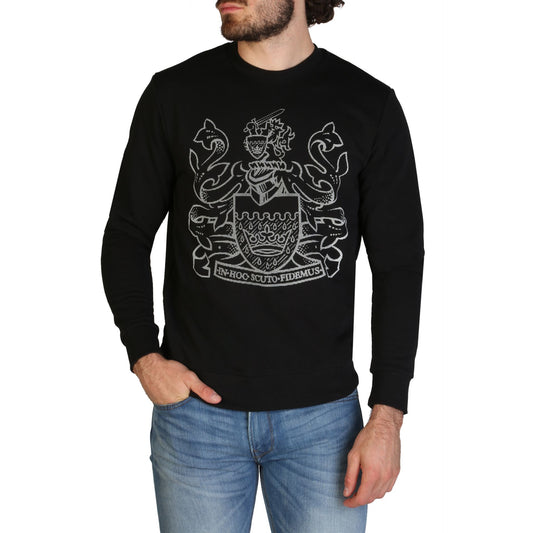 Elegant black sweatshirt featuring a detailed crest or coat of arms design in a contrasting light color, worn by a casually dressed man with facial hair against a plain background.